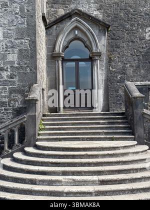 Steintreppen führen zu einem bogenförmigen Eingang eines Steingebäudes mit gotischen Architekturdetails in Kilkenny, Irland. Stockfoto