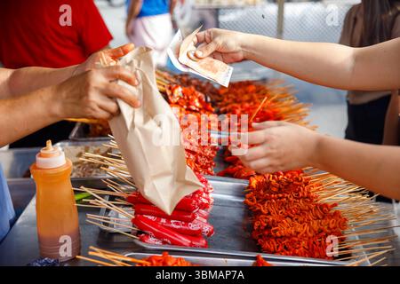 13. Mai 2025: Calapan City, Philippinen, Nahaufnahme von Händen, die Geld an einem Street Food-Stand austauschen Stockfoto