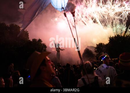 London, Großbritannien. Juni 2025. Die Green Fields Area des Glastonbury Festivals wird heute Abend mit einer Zeremonie eröffnet, die von der gemeinsamen „Flame of Hope“ geleitet wird und 15 heilige Flammen aus der ganzen Welt vereint. Ein Chor von über tausend Stimmen singt ein Friedensmantra in King's Meadow, gefolgt von einem spektakulären Feuerwerk. Die Veranstaltung schafft ein starkes Gefühl von Einheit und Zweck und markiert den offiziellen Beginn des Festivals in diesem ruhigen, spirituellen Herzen der Website Credit: Joao Daniel Pereira/Alamy Live News Stockfoto