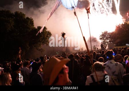 London, Großbritannien. Juni 2025. Die Green Fields Area des Glastonbury Festivals wird heute Abend mit einer Zeremonie eröffnet, die von der gemeinsamen „Flame of Hope“ geleitet wird und 15 heilige Flammen aus der ganzen Welt vereint. Ein Chor von über tausend Stimmen singt ein Friedensmantra in King's Meadow, gefolgt von einem spektakulären Feuerwerk. Die Veranstaltung schafft ein starkes Gefühl von Einheit und Zweck und markiert den offiziellen Beginn des Festivals in diesem ruhigen, spirituellen Herzen der Website Credit: Joao Daniel Pereira/Alamy Live News Stockfoto