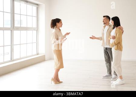 Immobilienmaklerin zeigt schwangeren Paaren neues Haus Stockfoto