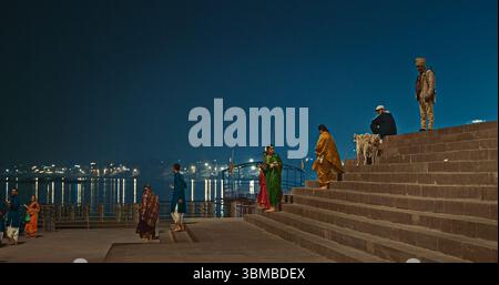 Varanasi, Uttar Pradesh, Indien - 6. Februar 2024: Menschen, die auf Uferdamm laufen, beleuchtet in den Dämmerungslichtern Stockfoto