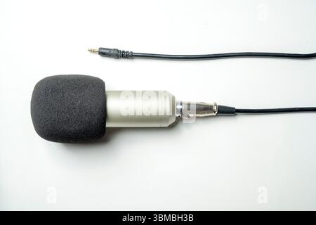 Studio-Mikrofon für Podcasting oder Streaming mit angeschlossenem Kabel auf weißem Hintergrund. Draufsicht Stockfoto