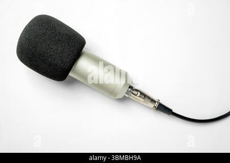 Studio-Mikrofon für Podcasting oder Streaming mit angeschlossenem Kabel auf weißem Hintergrund. Draufsicht Stockfoto