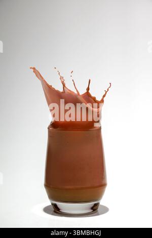Schokolade in einem Glas mit einem Spritzer auf weißem Hintergrund Stockfoto