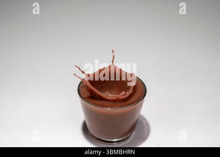 Schokolade in einem Glas mit einem Spritzer auf weißem Hintergrund Stockfoto