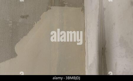 Verputzen einer Betonwand mit einem Spachtelmesser, Auffüllen von Mängeln und Erstellen einer glatten Oberfläche bei der Renovierung des Hauses Stockfoto