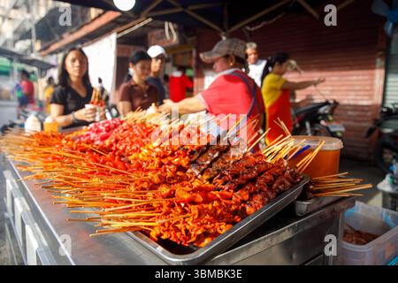 13. Mai 2025: Calapan City, Philippinen, gegrillte Fleischspieße am Marktstand mit Kunden, Street Food. Stockfoto