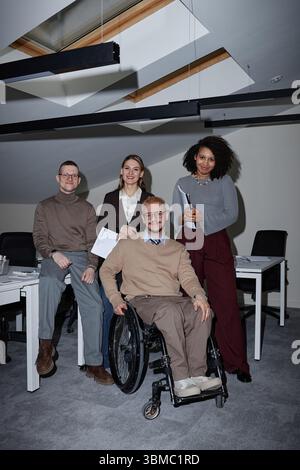 Verschiedene junge Erwachsene Kollegen arbeiten mit Kollegen mit Behinderung zusammen Stockfoto