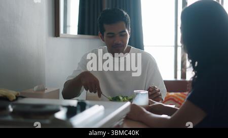 Partner teilen sich einen lebhaften Salat und genießen nahrhafte Mahlzeiten im eigenen Speisesaal Stockfoto