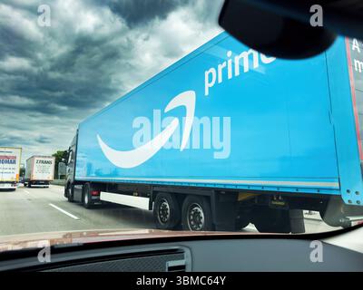 Frankfurt, Deutschland - 7. Mai 2025: Großer Amazon Prime Truck mit blauem Anhänger mit dem Prime-Logo fährt auf einer stark befahrenen deutschen Autobahn unter dramatischem Hintergrund Stockfoto