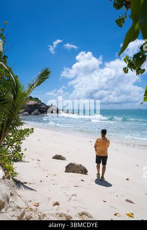Mahe Seychelles 23.06.25 Mann, der auf einer Tour auf den felsigen Strand blickt Stockfoto