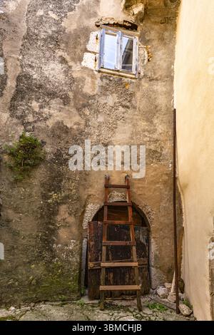 Bei einem Spaziergang durch die engen Gassen von Vrbnik auf der Insel KRK steht eine alte Holzleiter an einer Steinmauer Stockfoto