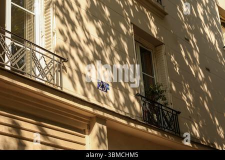 Ein Foto von einem Pariser Apartmentgebäude. Das Bild zeigt eine beigefarbene Gebäudefassade mit einem kleinen Balkon mit kunstvollem Metall Stockfoto