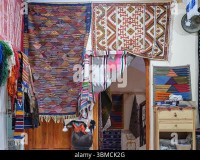 Marokko, Merzouga, 4. Juli 2025. Innenraum einer traditionellen Berber-Teppichwerkstatt in der Sahara, dekoriert mit farbenfrohen handgefertigten Teppichen und Webstoffen Stockfoto