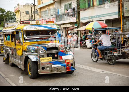 13. Mai 2025: Jeepney und Dreirad auf der geschäftigen Straße in Calapan City, Philippinen, Szene für den öffentlichen Nahverkehr Stockfoto