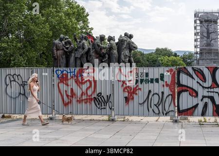 Sofia, Bulgarien. Juni 2025. Eine Frau geht mit ihrem Hund an dem teilweise demontierten und an Bord befindlichen Denkmal der sowjetischen Armee im Zentrum von Sofia vorbei, das zum Gedenken an den Einmarsch der Roten Armee in die bulgarische Hauptstadt errichtet wurde. Quelle: SOPA Images Limited/Alamy Live News Stockfoto