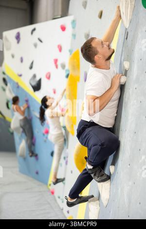 Junger Mann, der das Klettern an der Kletterwand übt Stockfoto