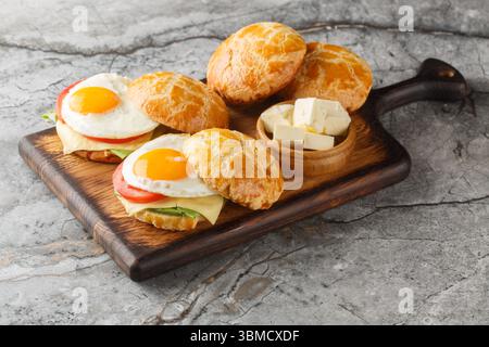 Ananasbrötchen Bolo Bao Egg Sandwich mit Tomaten, Käse, Salat in Nahaufnahme auf Holzbrett auf dem Tisch. Horizontal Stockfoto