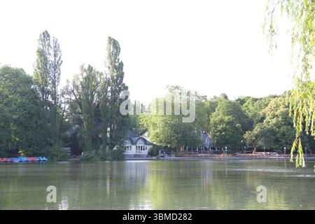 MÜNCHEN, DEUTSCHLAND - 24. JUNI 2025: Blick auf Bäume und Bootsverleih am Kleinhesseloher See im Englischen Garten in München Stockfoto