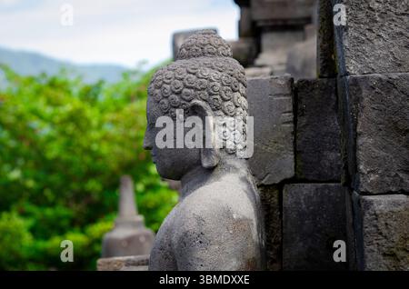 Die antike Buddha-Statue befindet sich inmitten von Steinruinen am Borobudur-Tempel, einem UNESCO-Weltkulturerbe. Stockfoto