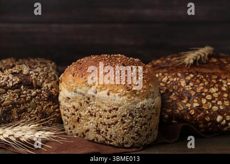 Frisch gebackene Brotlaibe und Stacheln auf Holztisch, Nahaufnahme Stockfoto