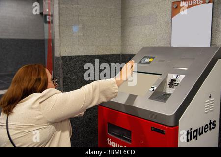 Frau, die Fahrkarten am Automaten in der U-Bahn-Station kauft. Inklusionskonzept, angepasster öffentlicher Verkehr Stockfoto