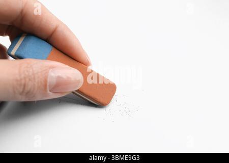 Frau benutzt Radiergummi auf weißem Papier, Nahaufnahme. Leerzeichen für Text Stockfoto