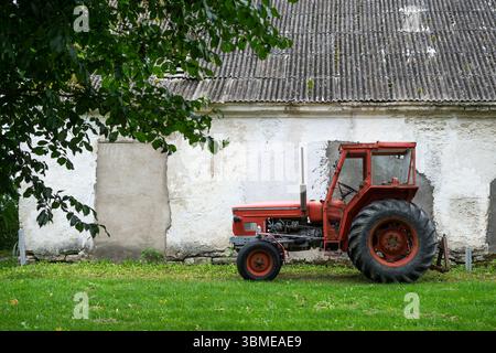 Roter Traktor vor der ländlichen Scheunenwand Stockfoto