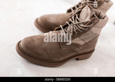 Beige Wildlederstiefel für Herren mit Schnürsenkeln auf weißem Hintergrund in Studio. Nahaufnahme der saisonalen Luxusschuhe für Herren. Details. Die Neue Winter Kollektion Footwe Stockfoto