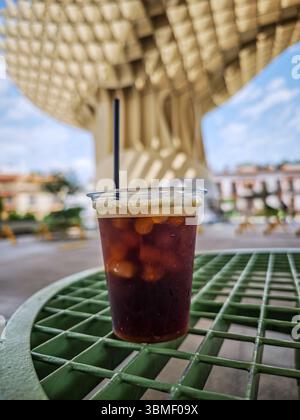 Eiskaffee steht auf einem grünen Tisch und bietet Erfrischungen im Schatten unter Las Setas in Sevilla. Eine perfekte Möglichkeit, sich abzukühlen. Stockfoto