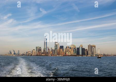 Panoramablick auf die Skyline von Lower Manhattan mit modernen Wolkenkratzern und Uferpromenade, vom Wasser aus gesehen an einem klaren Herbsttag mit blauem Himmel. Stockfoto