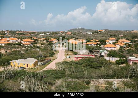 Üppige grüne Umgebung unterstreicht ein ruhiges Viertel mit leuchtenden orangen Dächern unter einem hellblauen Himmel. Stockfoto
