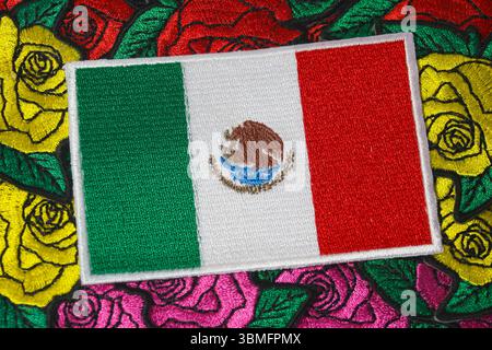 Umweltfreundliche, gestickte mexikanische Flagge auf farbenfrohen, handgefertigten Rosentextilien symbolisiert Kultur und nachhaltiges Handwerk. Stockfoto
