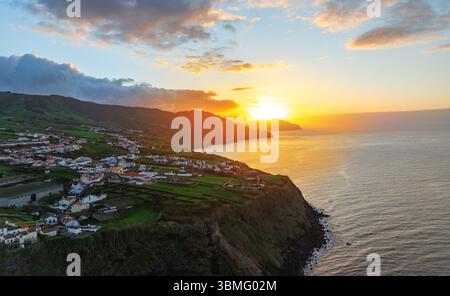 Aus der Vogelperspektive eines farbenfrohen Sonnenuntergangs über der dramatischen Küste der Insel São Miguel auf den Azoren, Portugal, mit grünen Feldern und dem Atlantischen Ozean Stockfoto