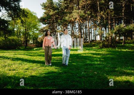 Ein paar Spaziergänge Hand in Hand durch einen ruhigen Wald an einem sonnigen Tag Stockfoto