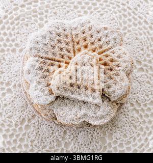Stapel frisch gebackener, hausgemachter Herzwaffeln mit Puderzucker, minimalistisch im Vintage-Stil Stockfoto