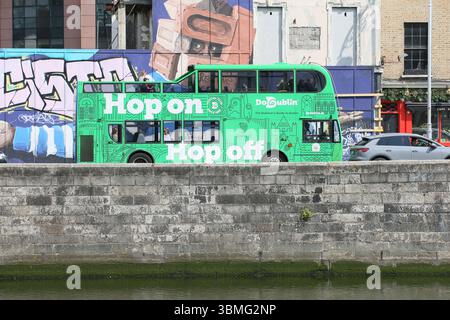 Dublin, Irland - 10. Juni 2025 - Ein grüner DoDublin Hop-on-Hop-off-Touristenbus fährt entlang der Quais des Flusses Liffey im Stadtzentrum von Dublin während einer sonnigen Zeit in der irischen Hauptstadt Stockfoto
