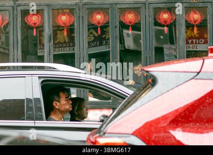 Chinatown Philadelphia, Pennsylvania, USA 5. Mai 2025: Ein chinesisches Café mit roten Laternen mit Kunden und einem Auto mit Fahrer und Beifahrer im Vorfeld Stockfoto
