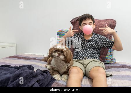 12-jähriger Teenager, der neben seinem Hund steht und auf das Zahnfleisch im Mund zeigt. Stockfoto