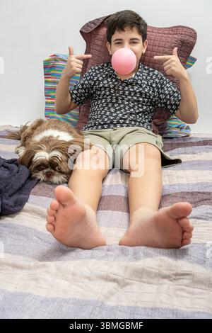 12-jähriger Teenager, der neben seinem Hund steht und auf das Zahnfleisch in seinem Mund zeigt. Stockfoto
