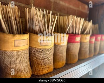 Rustikale Präsentation von essentiellen Duftstäbchen in Bio-gewebten Taschen, angeordnet auf einem Holzregal an einer alten Ziegelwand. Stockfoto