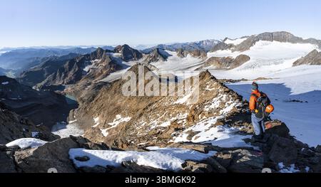 Bergsteiger auf einem felsigen Kamm auf dem Wilden Freiger Gipfel, hinter ihm Signalgipfel und Becher Gipfel mit Becherhaus, malerische Hochgebirgslandschaft Stockfoto