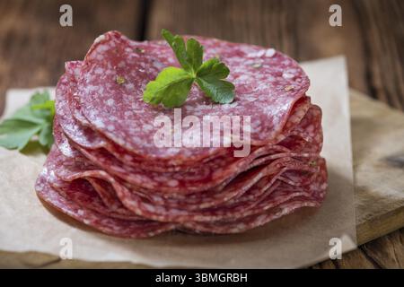 Scheiben Salami (Tiefenschärfe) auf einem alten Holztisch vintage Stockfoto