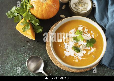 Vegetarische Kürbis- und Karottencreme-Suppe mit Sahne und Kürbiskernen auf einem Steintisch. Comfort Food, Herbst und Winter gesundes Slow Food Konzept. Co Stockfoto
