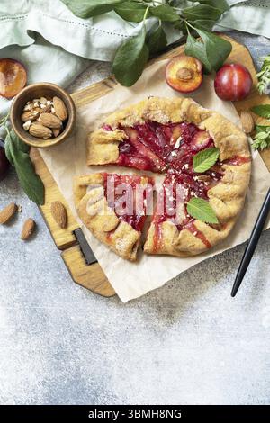 Plum Galette. Gesunder hausgemachter Vollkornfruchtkuchen (Galette) mit Pflaumen und Mandeln, veganes vegetarisches Dessert auf einem Steintisch. Blick von oben. Kopieren Stockfoto