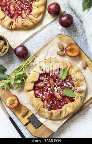 Pflaumengalette. Gesunder hausgemachter Vollkornobstkuchen (Galette) mit Pflaumen und Mandeln, veganes vegetarisches Dessert auf einem Steintisch. Blick von oben Stockfoto