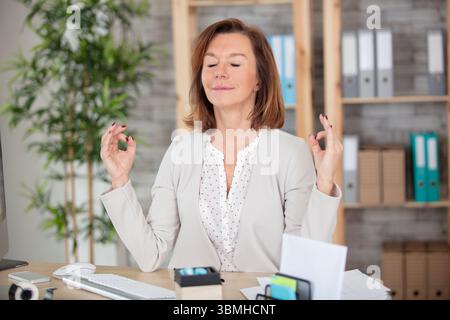 Leitende Büroangestellte meditiert in ihrem Büro Stockfoto