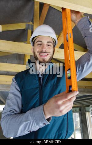 baumeister verwendet Wasserwaage zur Überprüfung des Dachträgers Stockfoto