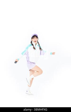 Eine fröhliche Studentin springt in die Luft und hält ihr Handy. Stockfoto